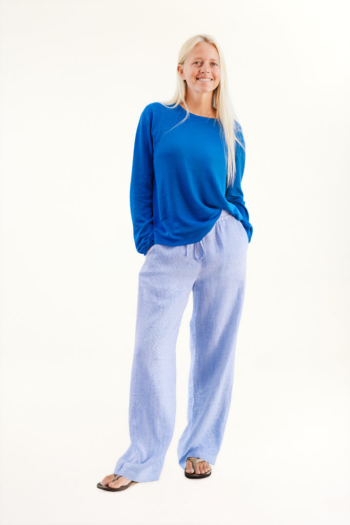 Woman wearing a blue top and light blue pants on a white background