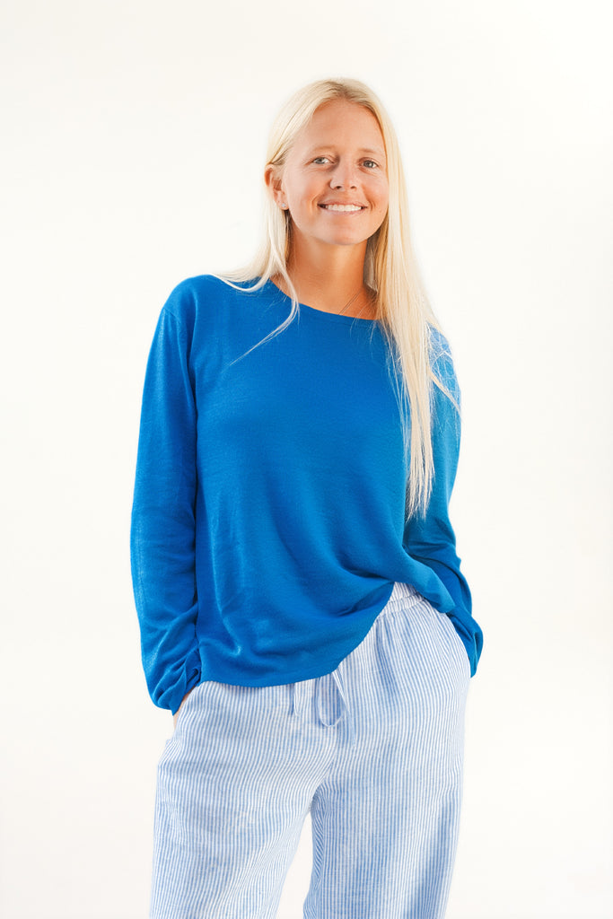 Woman wearing a blue sweater and light blue pants on a white background