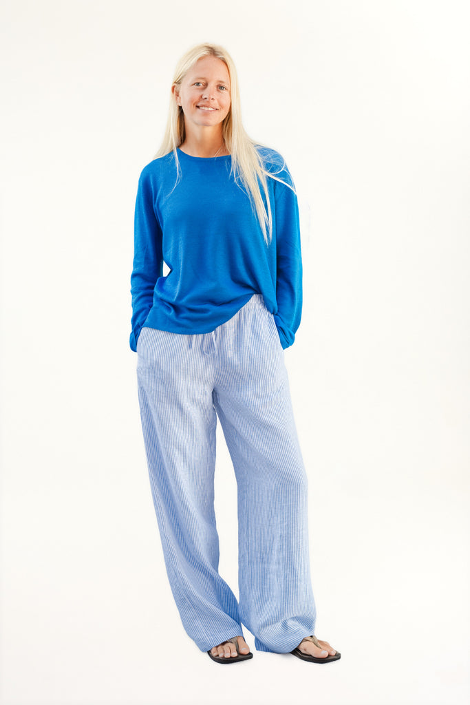 Woman wearing a blue top and light blue pants on a white background