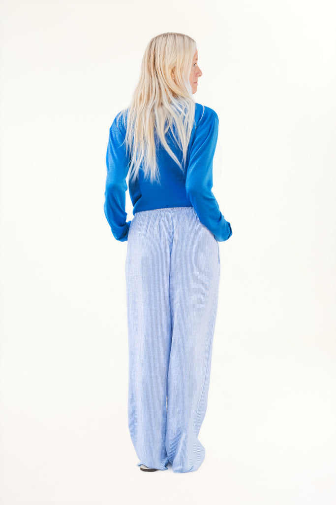 Person wearing a blue top and light blue pants on a white background