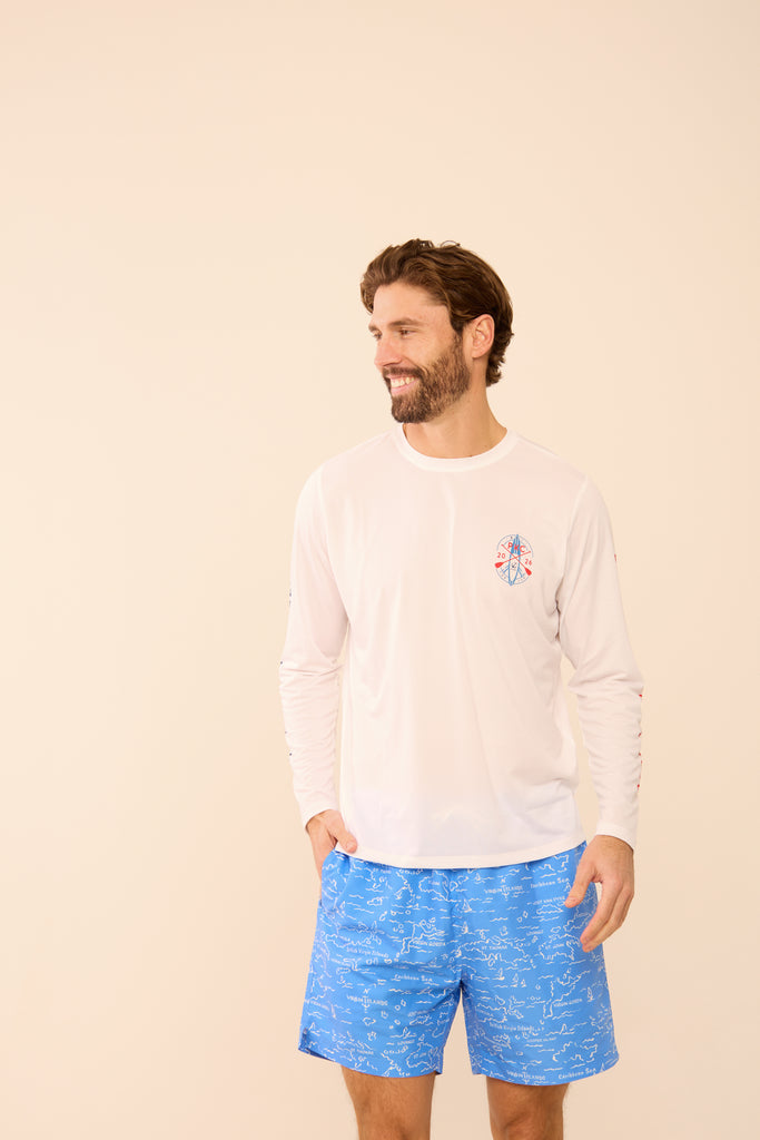 Man wearing a white long-sleeve shirt and HIHO VI Map blue patterned shorts on a beige background