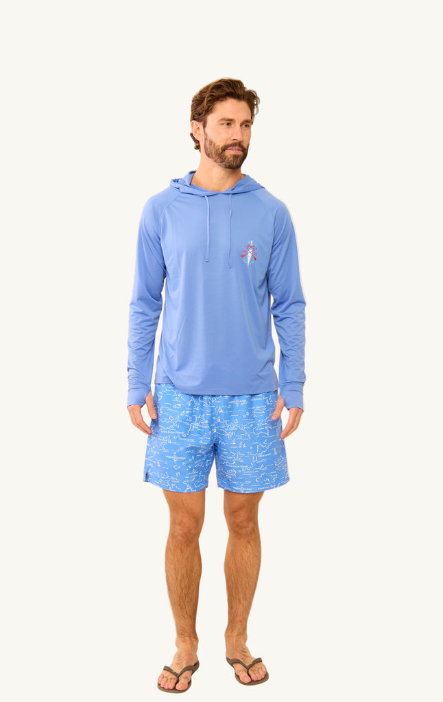 Man wearing a blue hoodie and VI Map shorts on a beige background