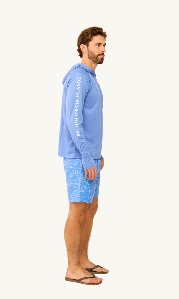 Man wearing a blue hoodie and patterned shorts on a beige background